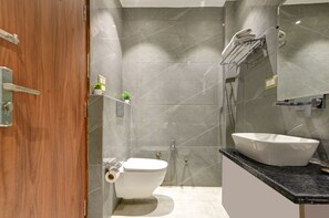 Uma casa de banho moderna com sanita, lavatório e chuveiro.