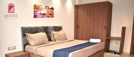 Habitación de hotel con cama, mesita de noche, armario y un cuadro en la pared.