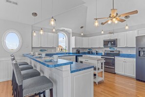 A modern kitchen with white cabinets, a blue countertop, and a central island with bar stools.