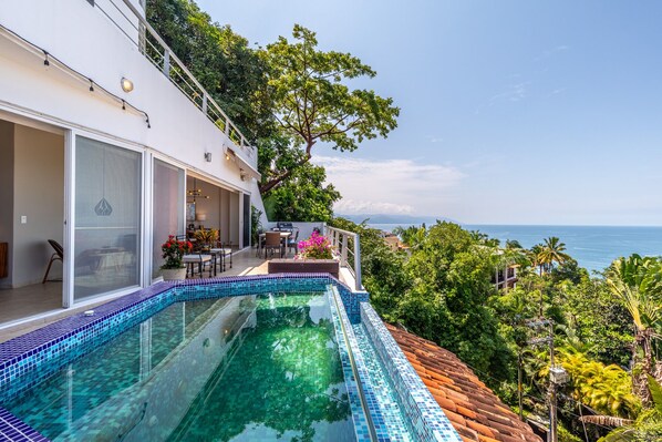 Una casa moderna con piscina infinita de vidrio que domina el mar.