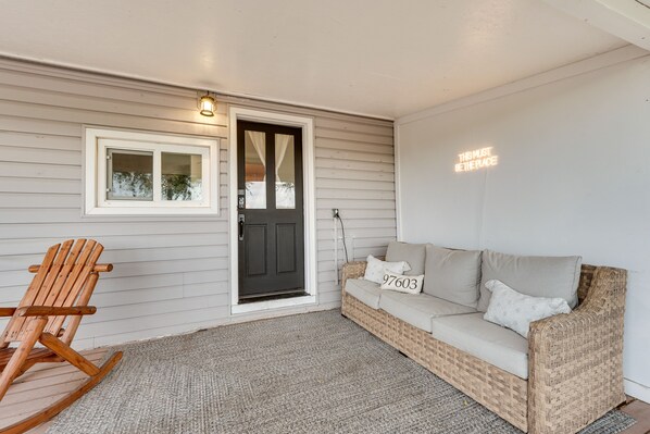 A cozy entryway with a wicker sofa, a rocking chair, and a door with a frosted glass window. - Klamath Falls Home on 189 Acres: Fire Pit & Grill! (Midland)