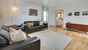 Una sala de estar moderna con un sofá de cuero negro, un tapete blanco y un mueble de madera.