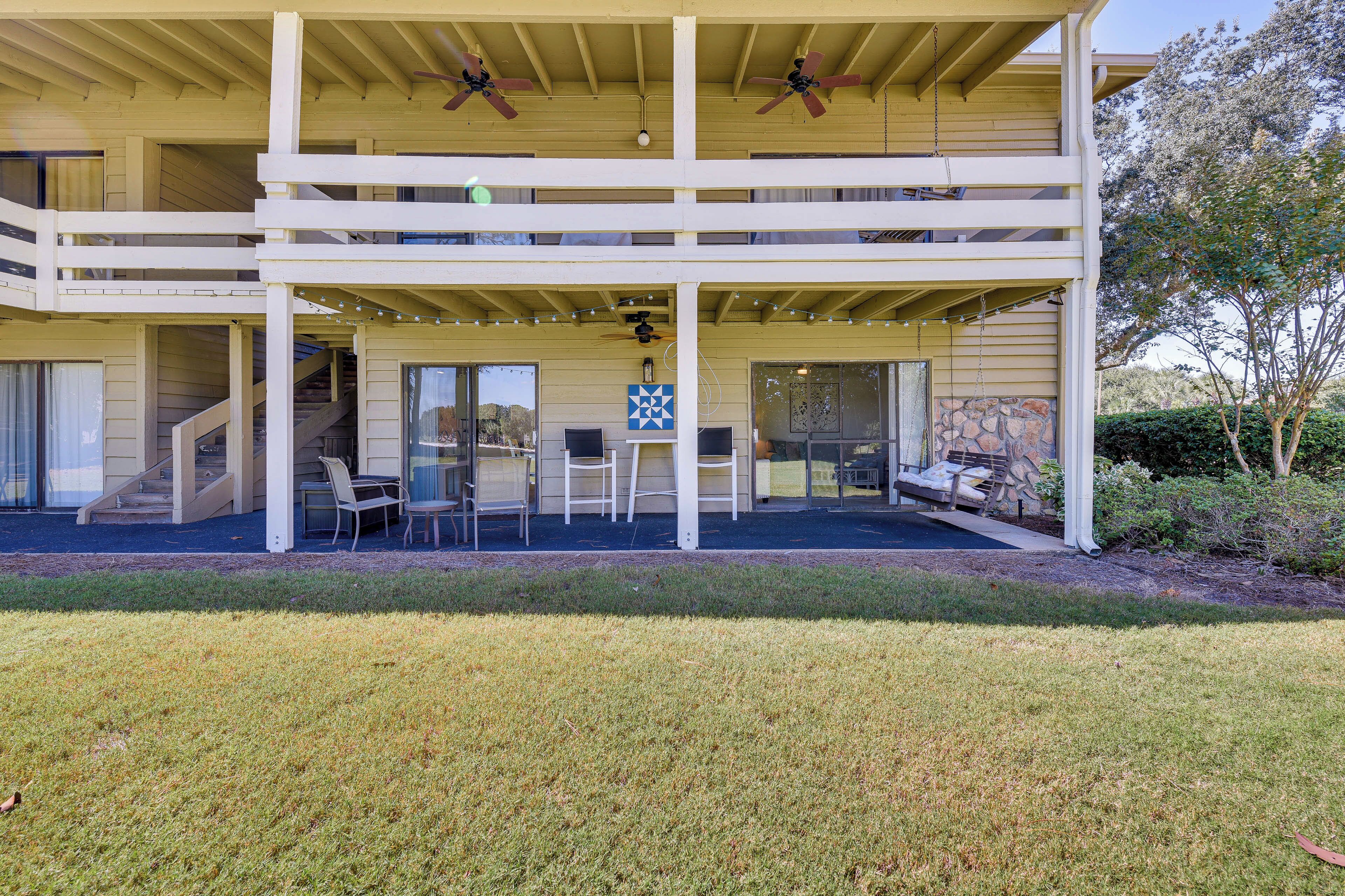 A two-story building with a covered patio area featuring outdoor seating and a staircase leading to the upper level.