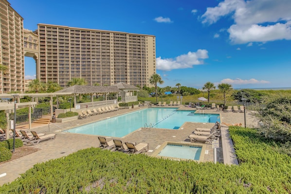 Um hotel com uma grande área de piscina, várias espreguiçadeiras e vista para o oceano.