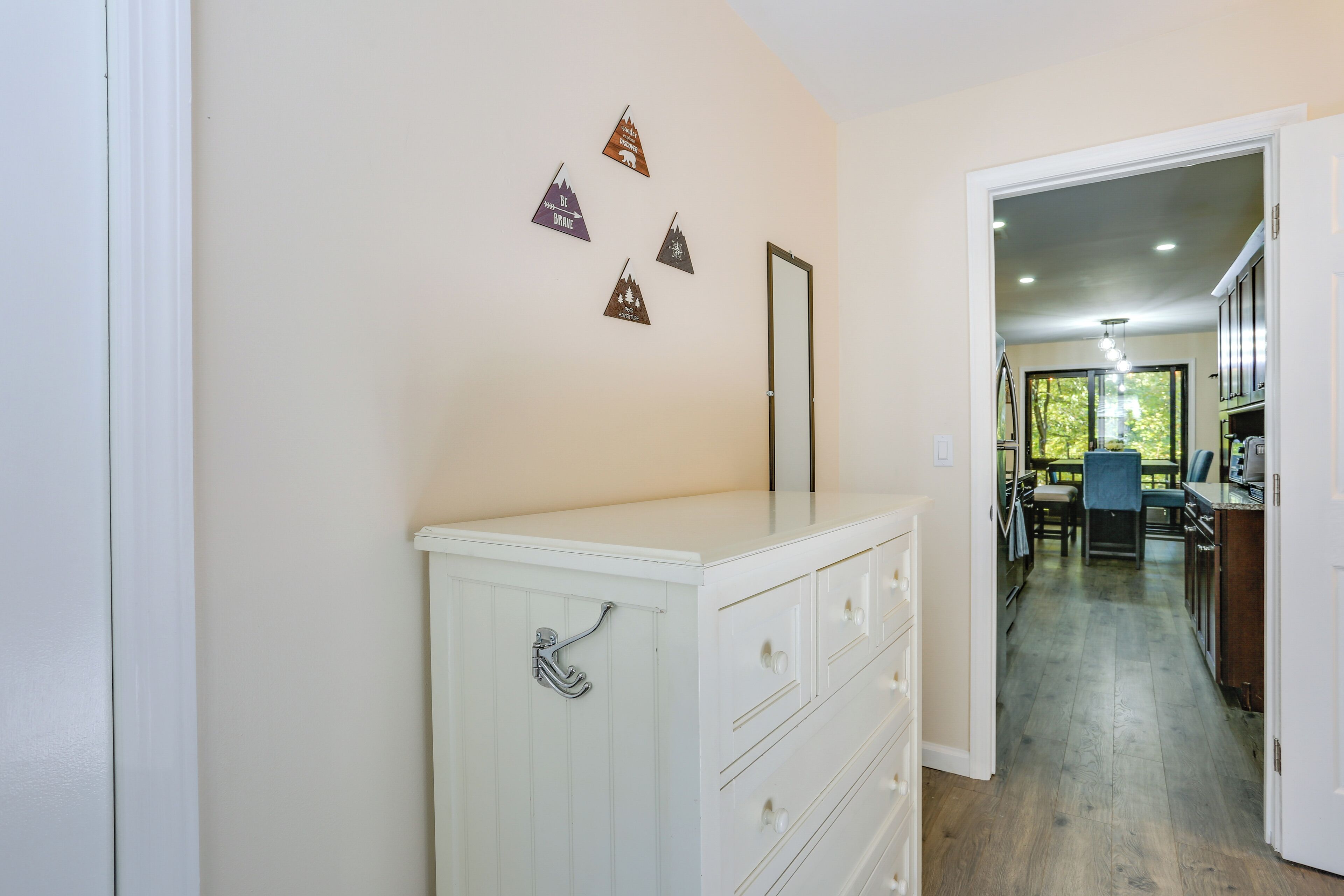 Een gang met een witte dressoir, een spiegel en vier decoratieve driehoeken aan de muur.