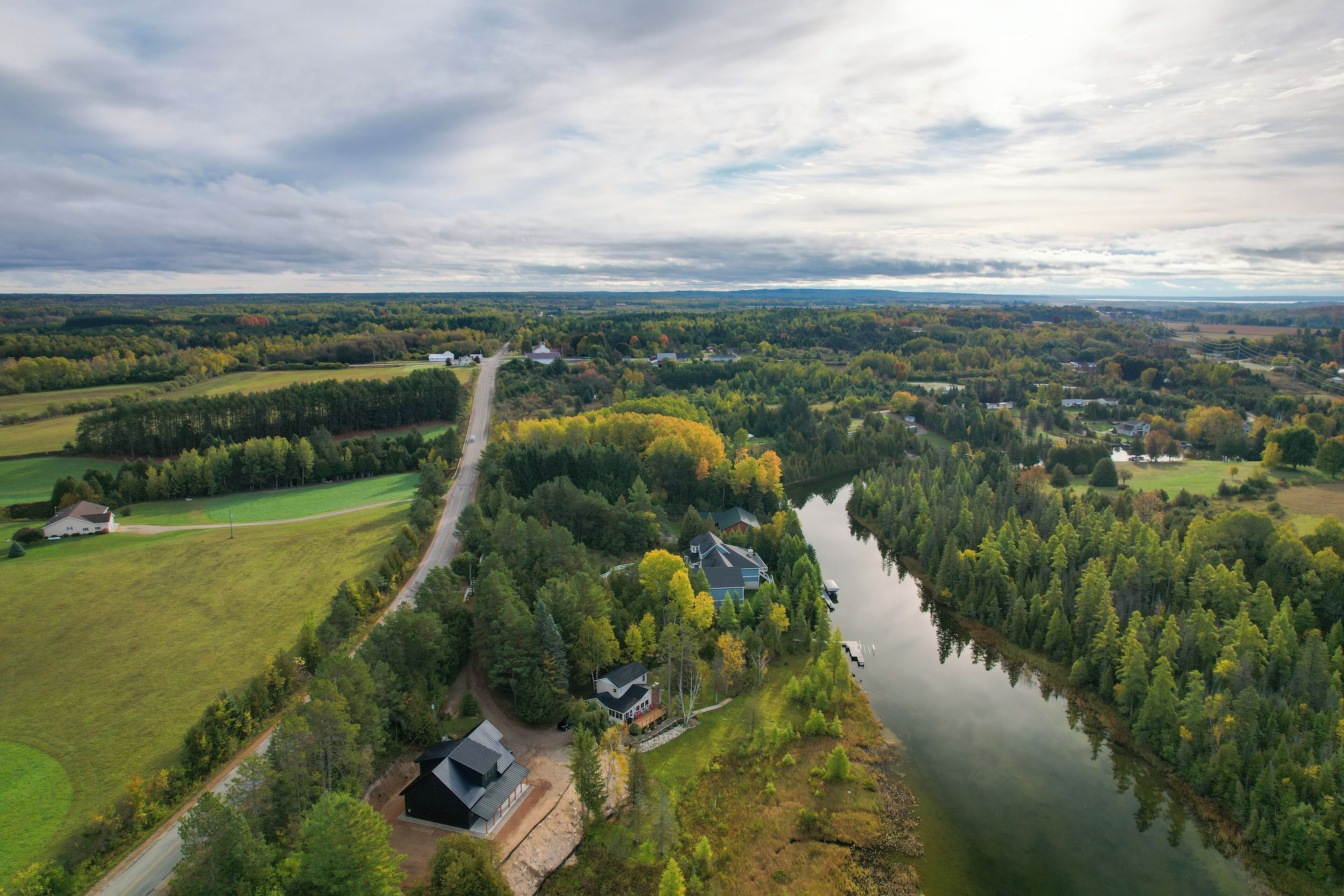 A river flowing through a forested area with houses along the riverbank.