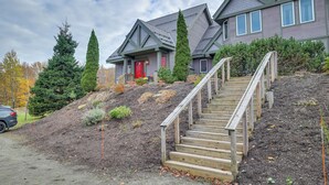 Ein zweistöckiges Haus mit roter Tür, einer Treppe mit Holzgeländern und einer Auffahrt.