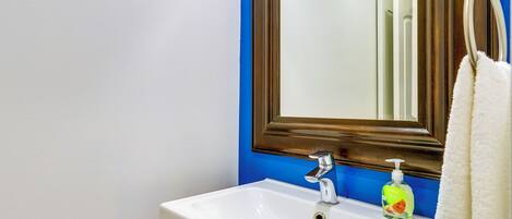 A bathroom with a white sink, a blue wall, and a wooden-framed mirror.