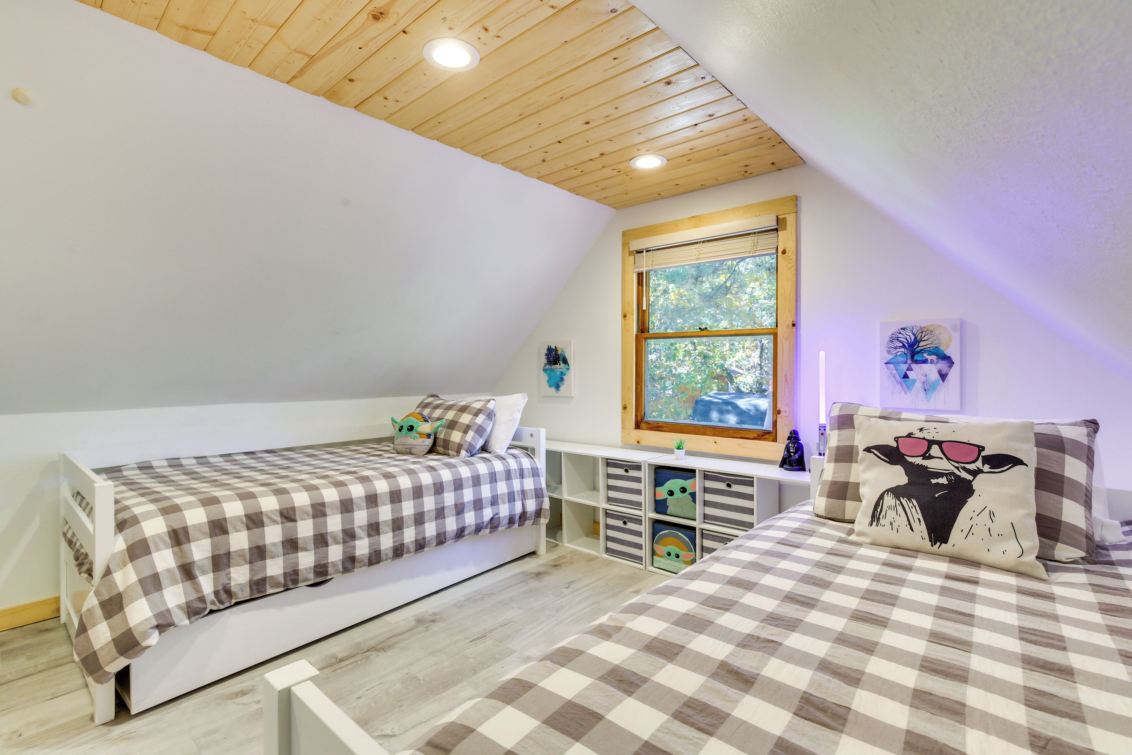 A bedroom with two beds, a window, and a ceiling with wooden beams.