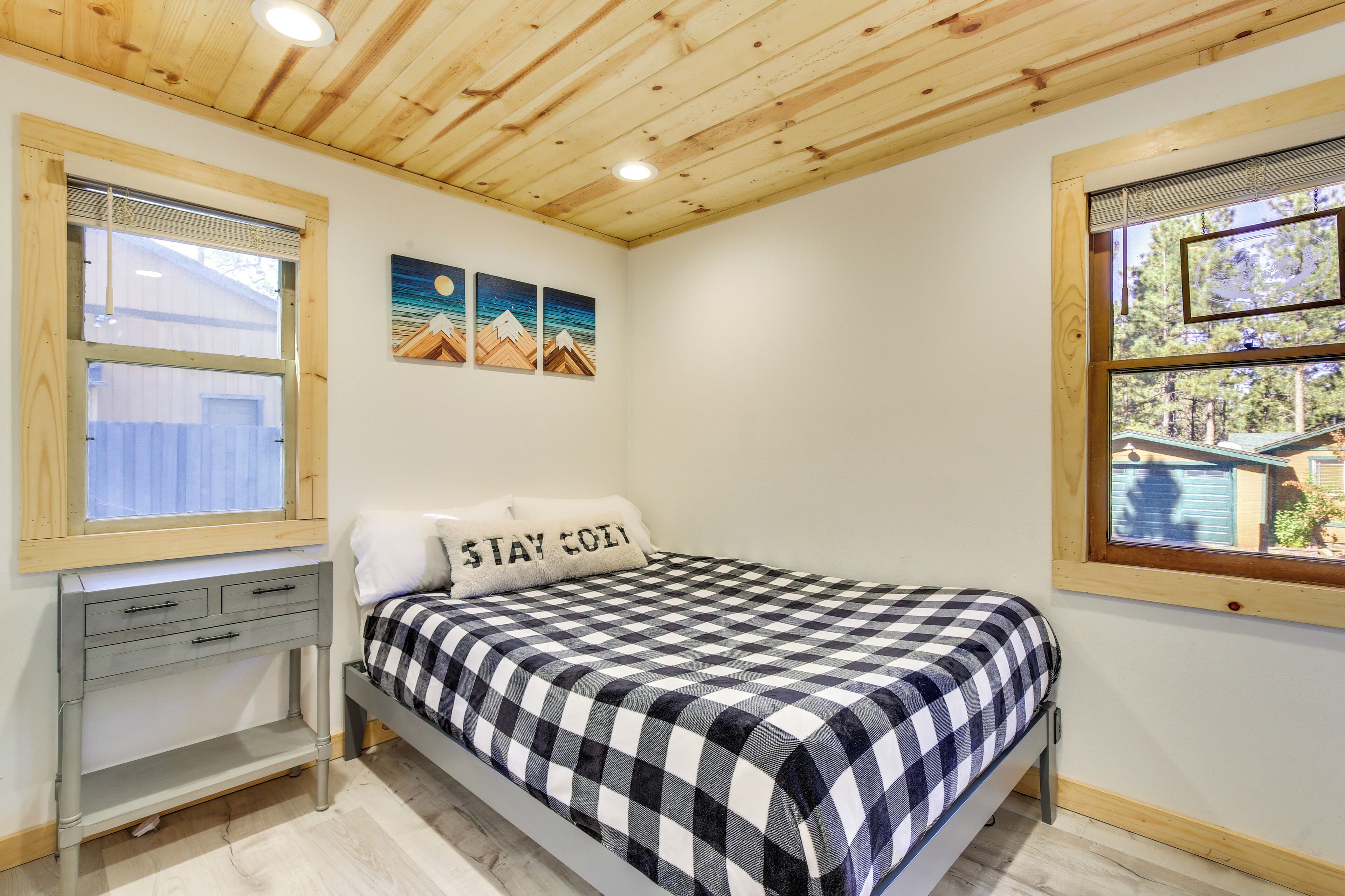 A bedroom with a bed, a desk, and a window.