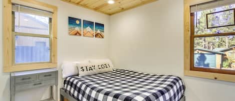 A bedroom with a bed, a desk, and a window.