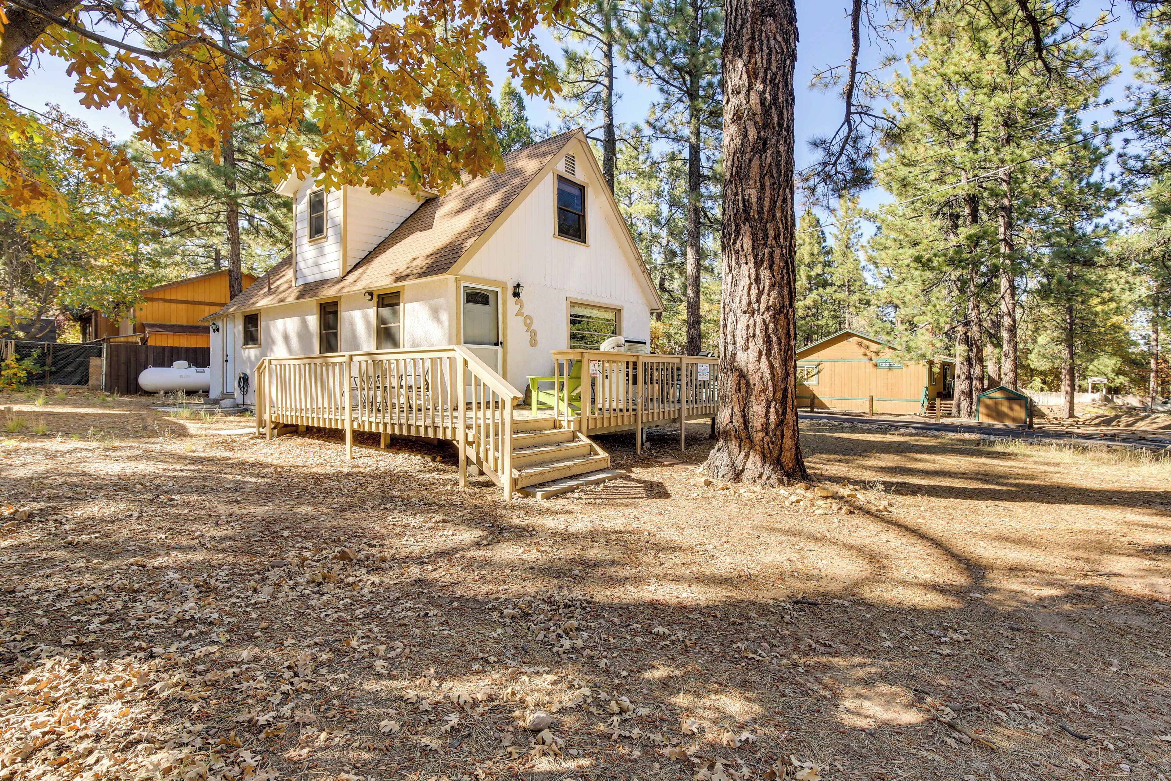 A cabin with a wooden deck, a covered porch, and a small staircase leading to the entrance.