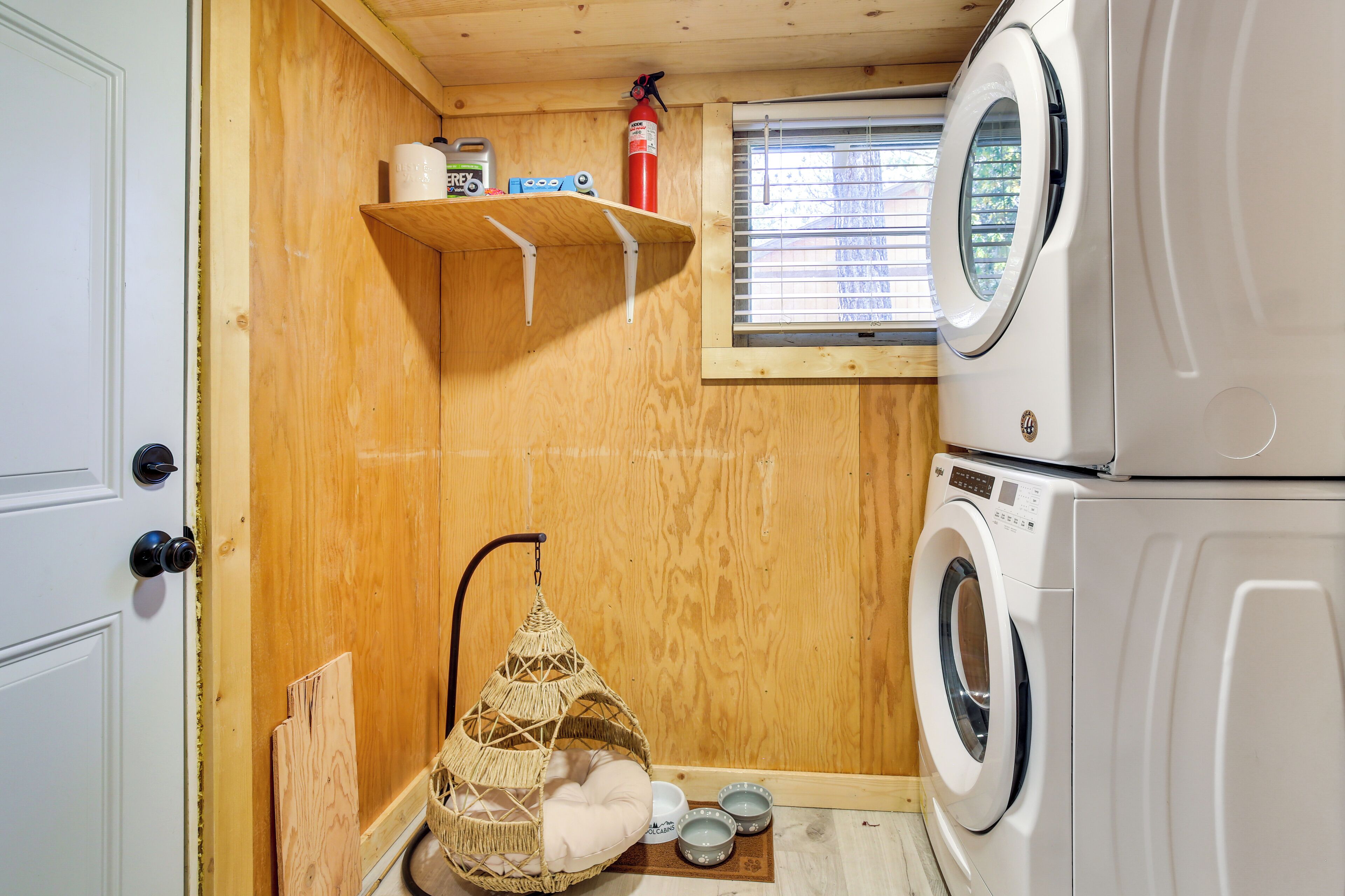A compact laundry room with a washing machine, a drying rack, and a small shelf with cleaning supplies.