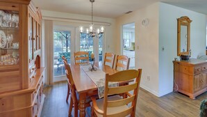 A dining area with a wooden table, chairs, and a chandelier. There is a wooden cabinet with glassware on the left. - 2 Mi to Rainbow River: Home in Dunnellon (Dunnellon)