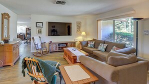 A spacious living room with a large TV, comfortable seating, a wooden dining table, and a view through large windows. - 2 Mi to Rainbow River: Home in Dunnellon (Dunnellon)
