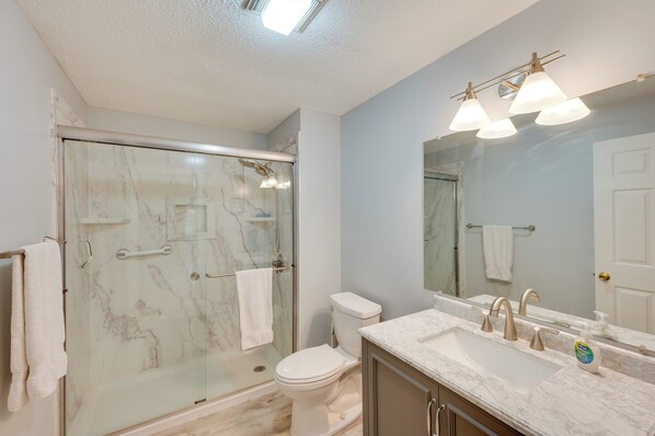 A bathroom with a glass-enclosed shower, a toilet, a sink with a mirror, and a towel rack. - Inviting Bartlett Condo: 1 Mi to Attitash Mountain (Bartlett)