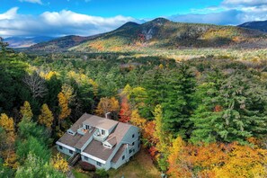 A two-story house with a sloped roof, surrounded by dense forest and autumn foliage. - Inviting Bartlett Condo: 1 Mi to Attitash Mountain (Bartlett)