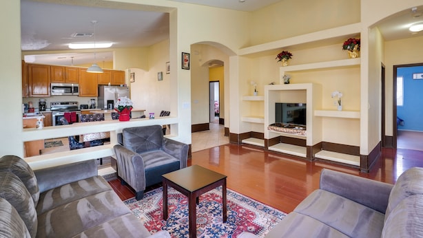 A spacious living room with a fireplace, a kitchen in the background, and a ceiling fan. - Families w/ Pet Welcome! Home 7 Mi to Chase Field (Phoenix)