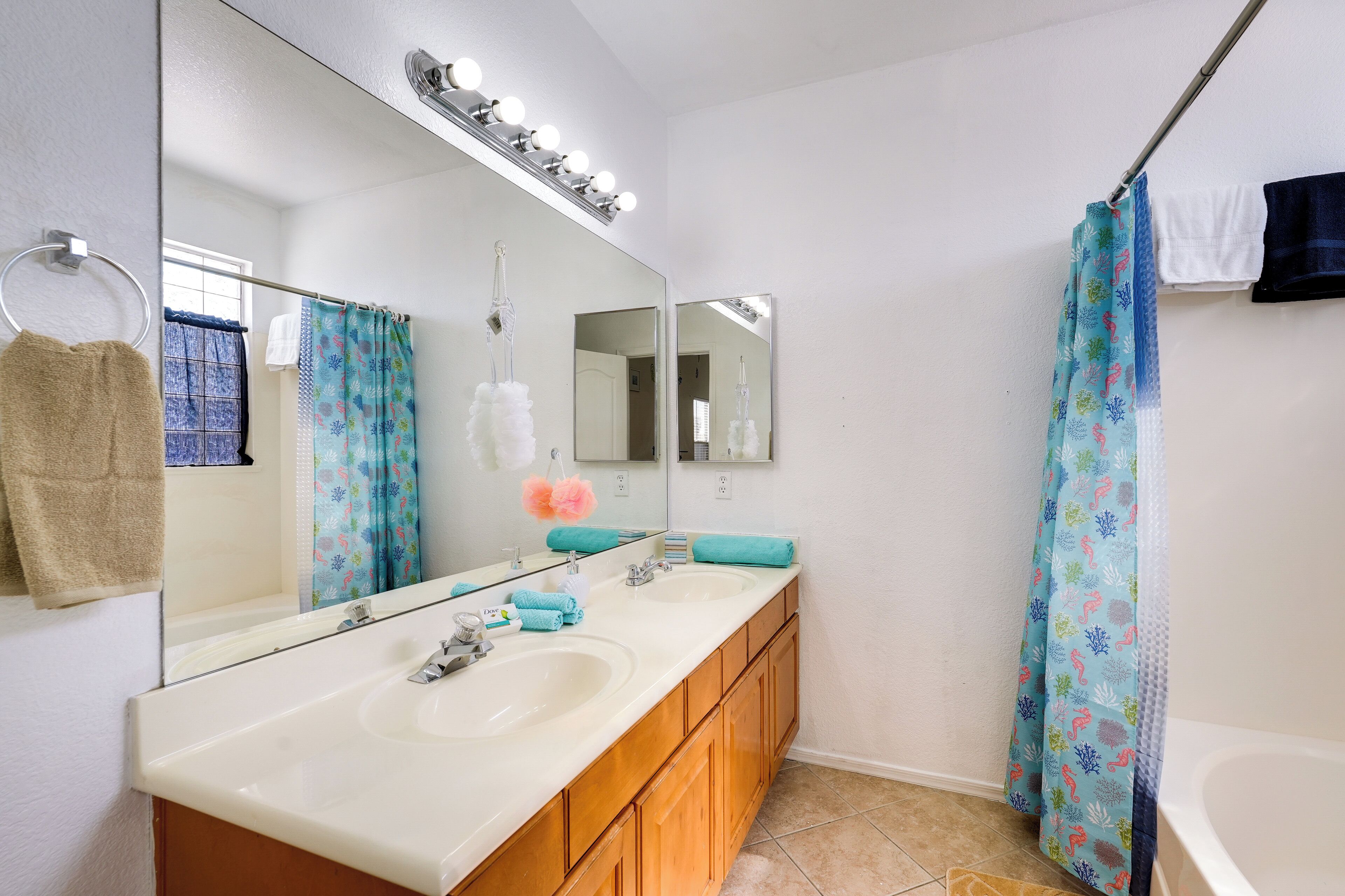 A bathroom with two sinks, a large mirror, and a shower curtain.