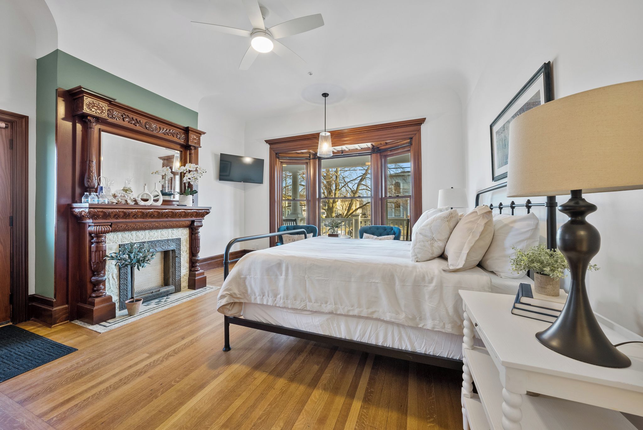 Drift into restful sleep in this airy bedroom with elegant hardwood floors, a stately fireplace, and soft natural light streaming through charming windows. Crisp linens and classic touches make it your peaceful retreat.