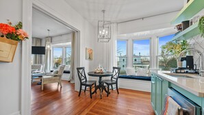 A modern kitchen with a dining area, wooden flooring, and large windows offering a view of the city. - Elegant Boutique Condo Downtown Sandusky (Sandusky)