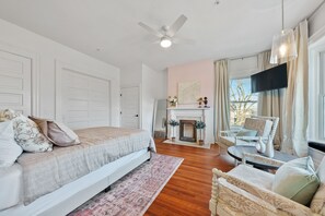 Un dormitorio con una cama, una silla, una chimenea y un televisor.