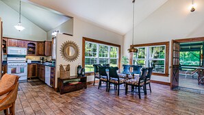 Une cuisine spacieuse avec des meubles en bois, une grande fenêtre et un coin repas comprenant une table et des chaises en bois.