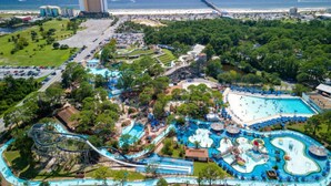 An aerial view of a theme park with a large water park, a parking lot, and a beach area. - 🌞Carillon Beach Resort Inn 414 - Chasing Sunsets | Lakefront + Walk to Beach (Panama City Beach)