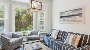A living room with a large window, a sofa, two armchairs, and a coffee table.