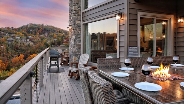 Una terraza con una chimenea, asientos exteriores y vistas panorámicas de una zona montañosa.