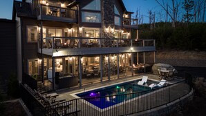 Una casa de dos pisos con piscina, mobiliario exterior y fachada de piedra.