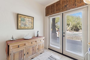 A room with a wooden cabinet, a framed picture, and a sliding glass door with blinds. - Rancho Villa - Southwestern home in Rancho Manana (Cave Creek)