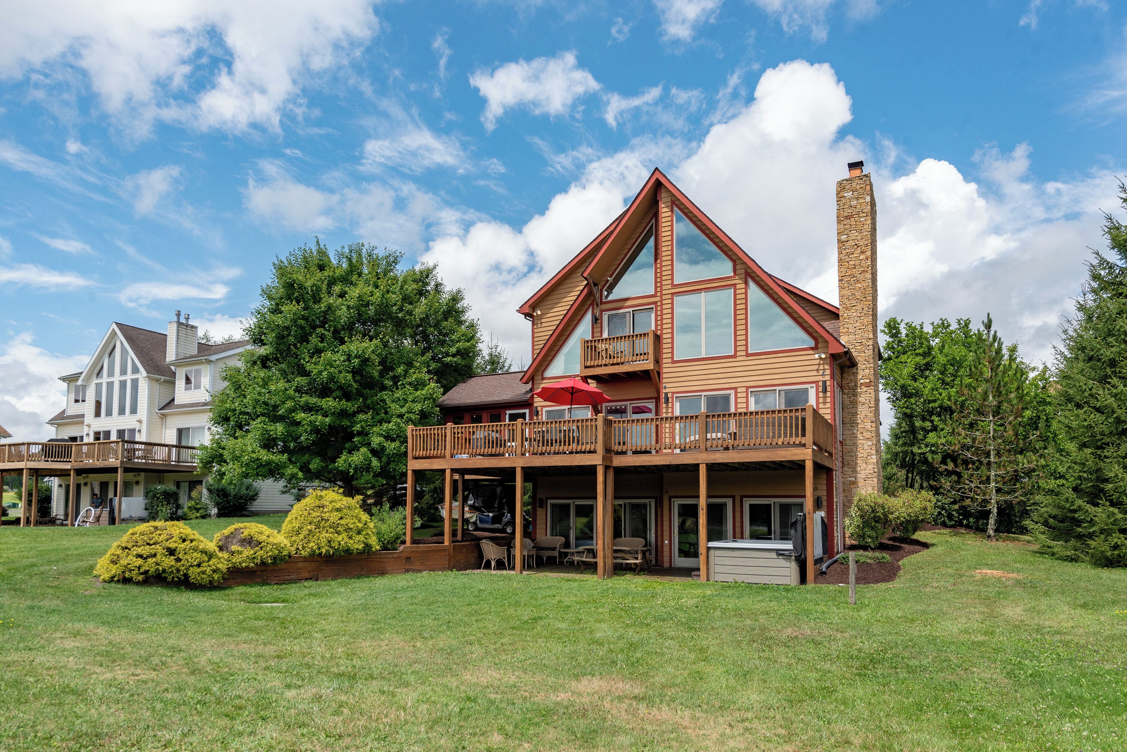 Une maison à deux étages avec un balcon, une cheminée et une pelouse bien entretenue.