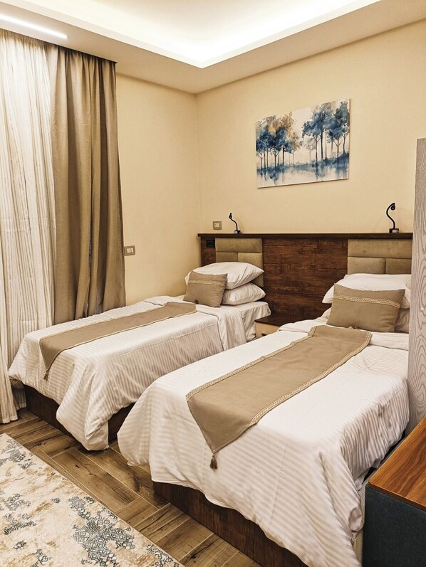Habitación de hotel con dos camas, cabecera de madera, un cuadro en la pared y una alfombra estampada.