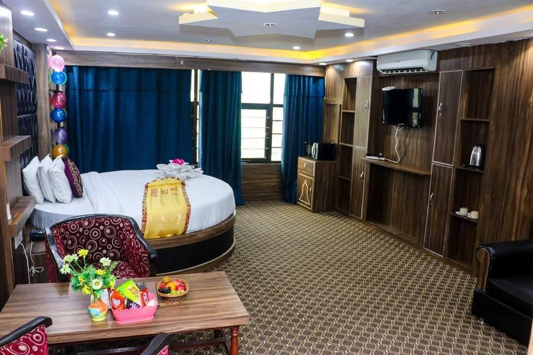 Ein Hotelzimmer mit einem großen Bett, einem Schreibtisch mit einer Vase und Snacks, einem Fernseher und Holzmöbeln.