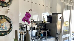 Ett modernt kök med vita skåp, rostfria vitvaror och en bänkskiva i marmor.