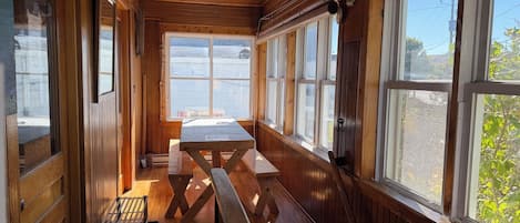 A wooden cabin interior with a bench, large windows, and a ceiling light.