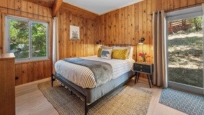 Una camera da letto con rivestimento in legno, un letto, un comodino e una finestra.