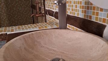 A bathroom with a round sink, a mirror, and tiled walls.