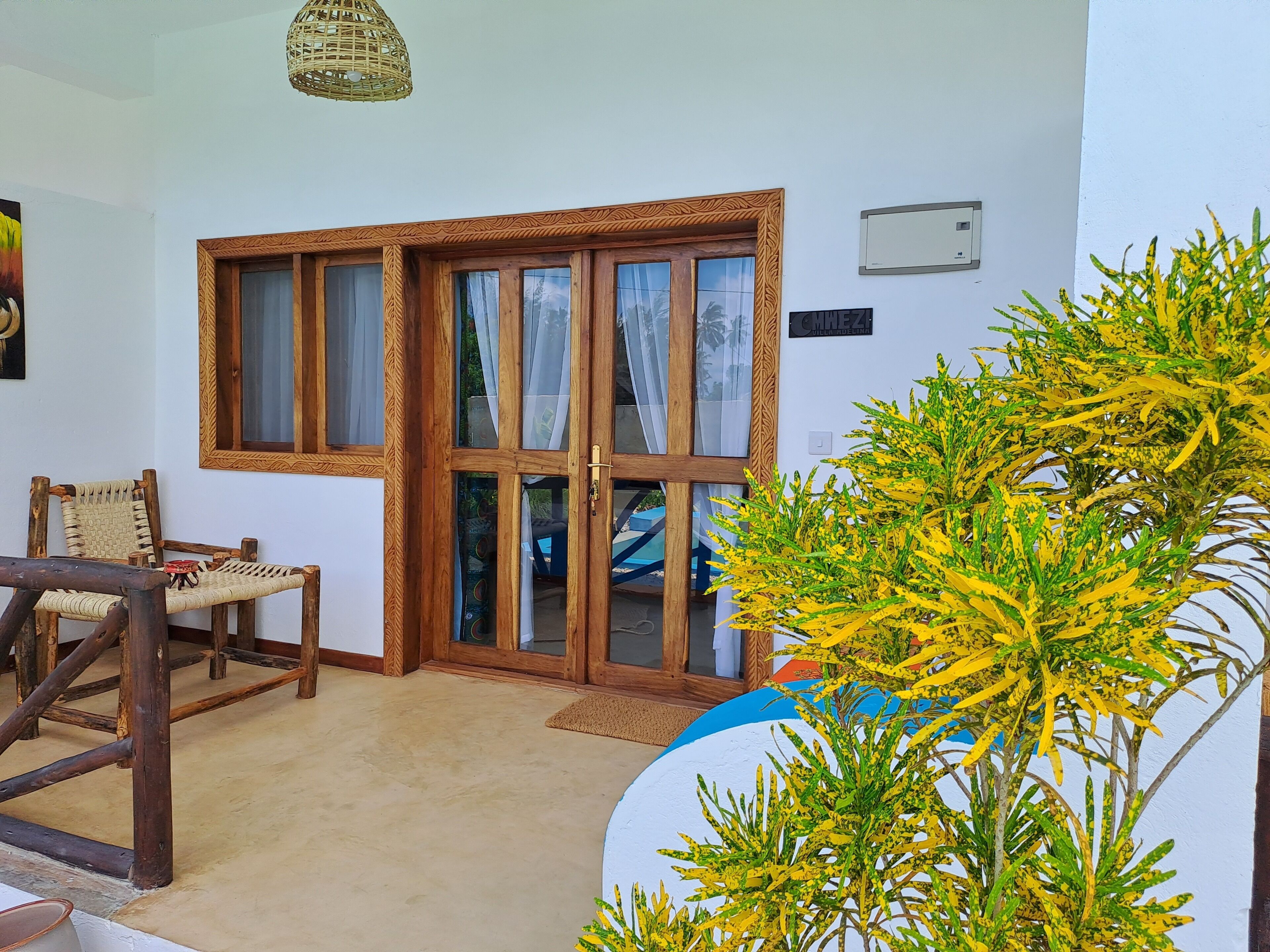 A room with a wooden-framed sliding glass door, a woven chair, and a large plant.