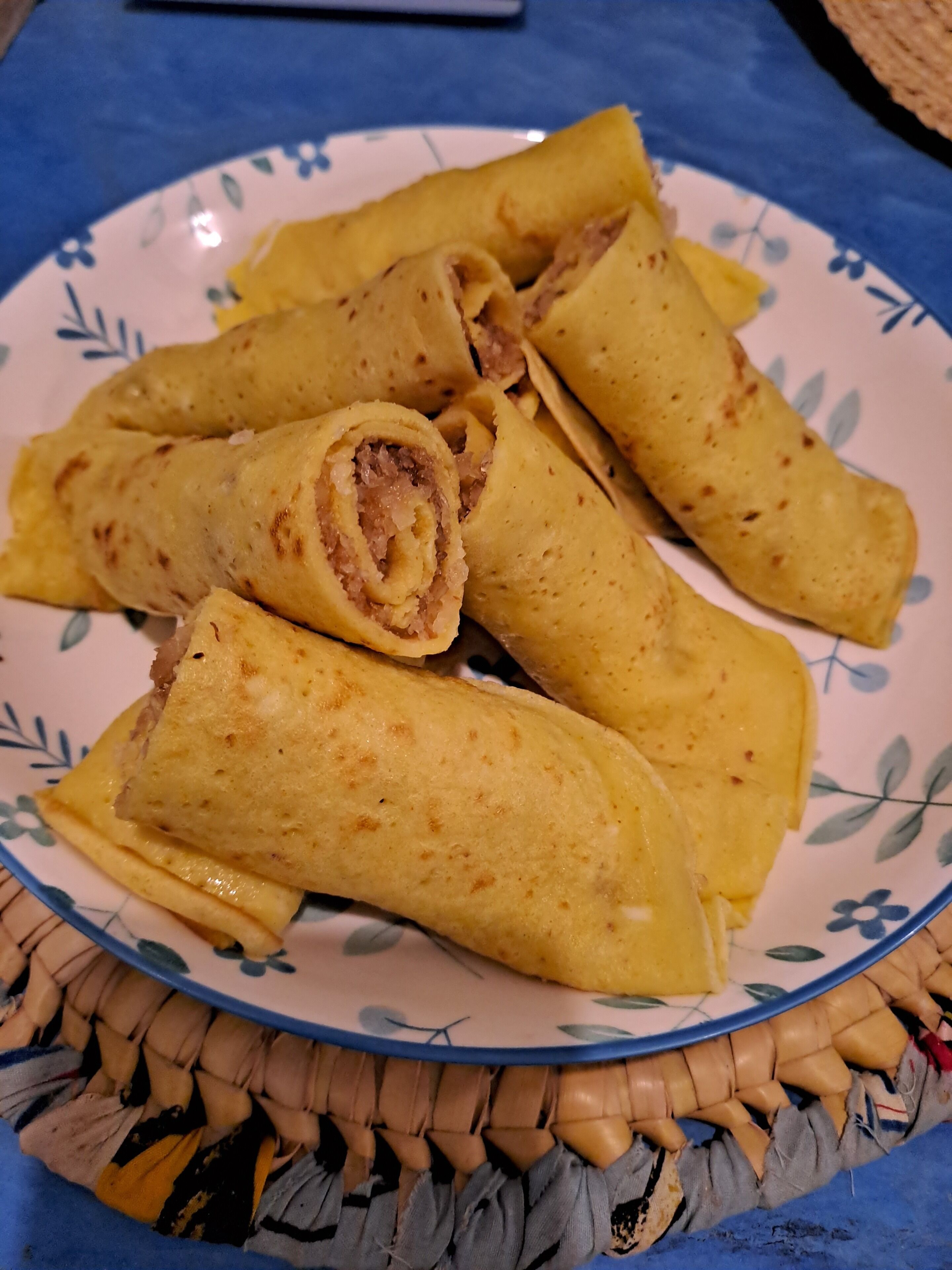 A plate of rolled food items, possibly spring rolls, on a decorative plate.