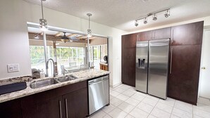 Una cocina moderna con un refrigerador de acero inoxidable, lavavajillas y encimera de mármol.