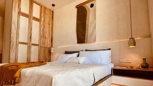 Ein Schlafzimmer mit einem großen Bett, einem Nachttisch, einem Deckenventilator und einer Wandleuchte.
