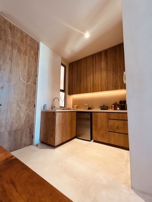 A modern kitchen with wooden cabinetry, a built-in dishwasher, and a countertop with various kitchen items.