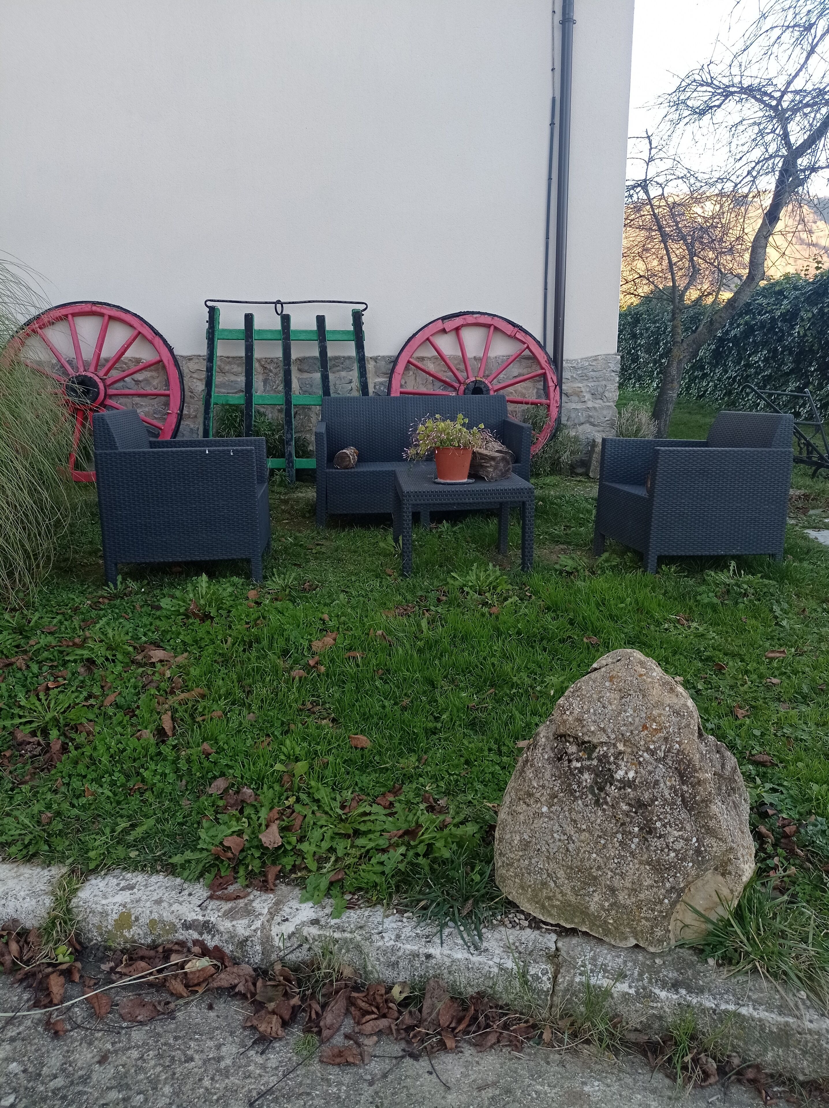 A garden area with outdoor furniture, a stone wall, and two large red wheels.