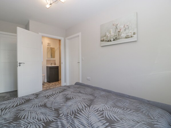 Un dormitorio con una cama, una puerta que da al baño y un cuadro en la pared.