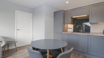 A modern kitchen with grey cabinets, a round dining table, and two grey chairs.