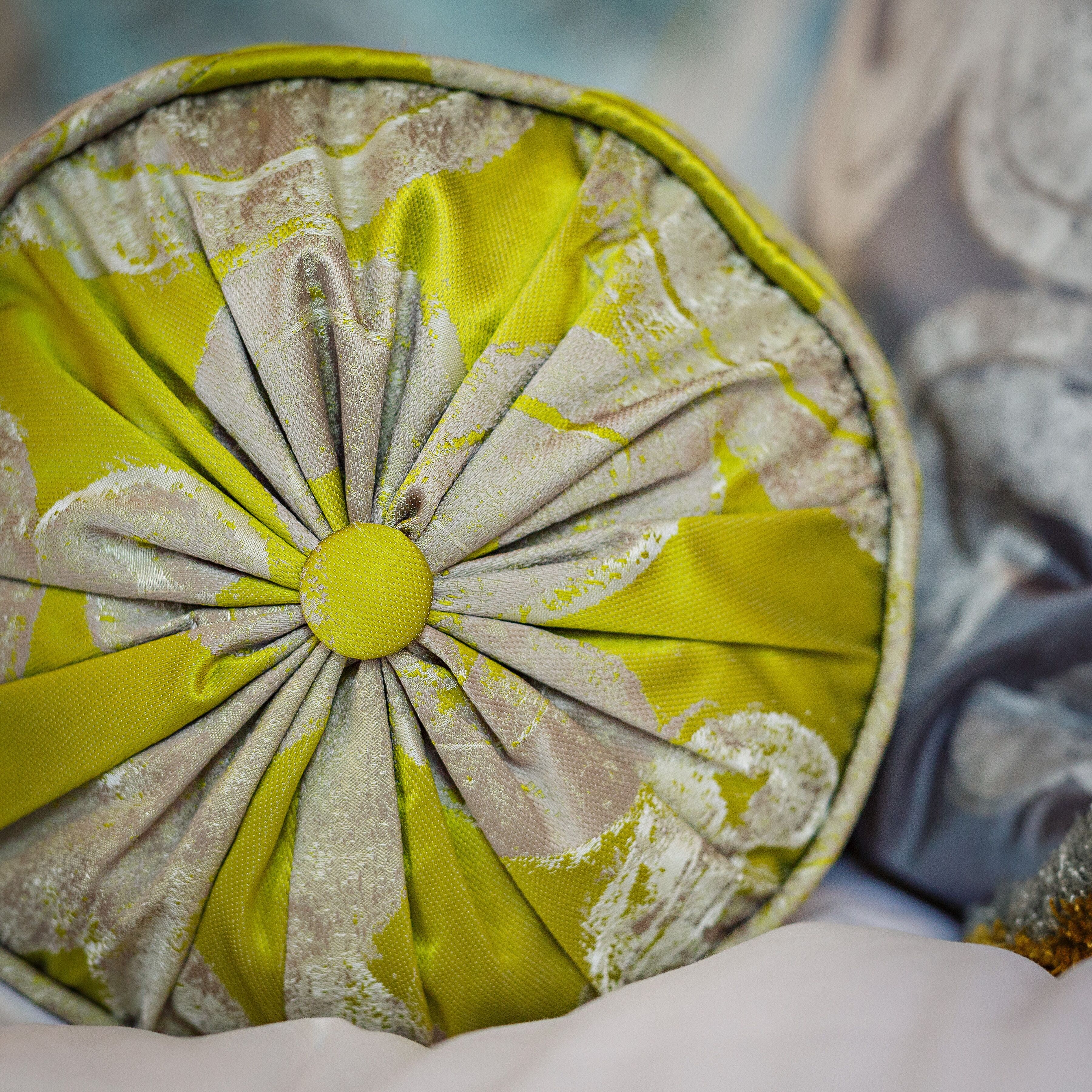 A circular cushion with a yellow and white fabric design.