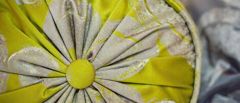A circular cushion with a yellow and white fabric design.