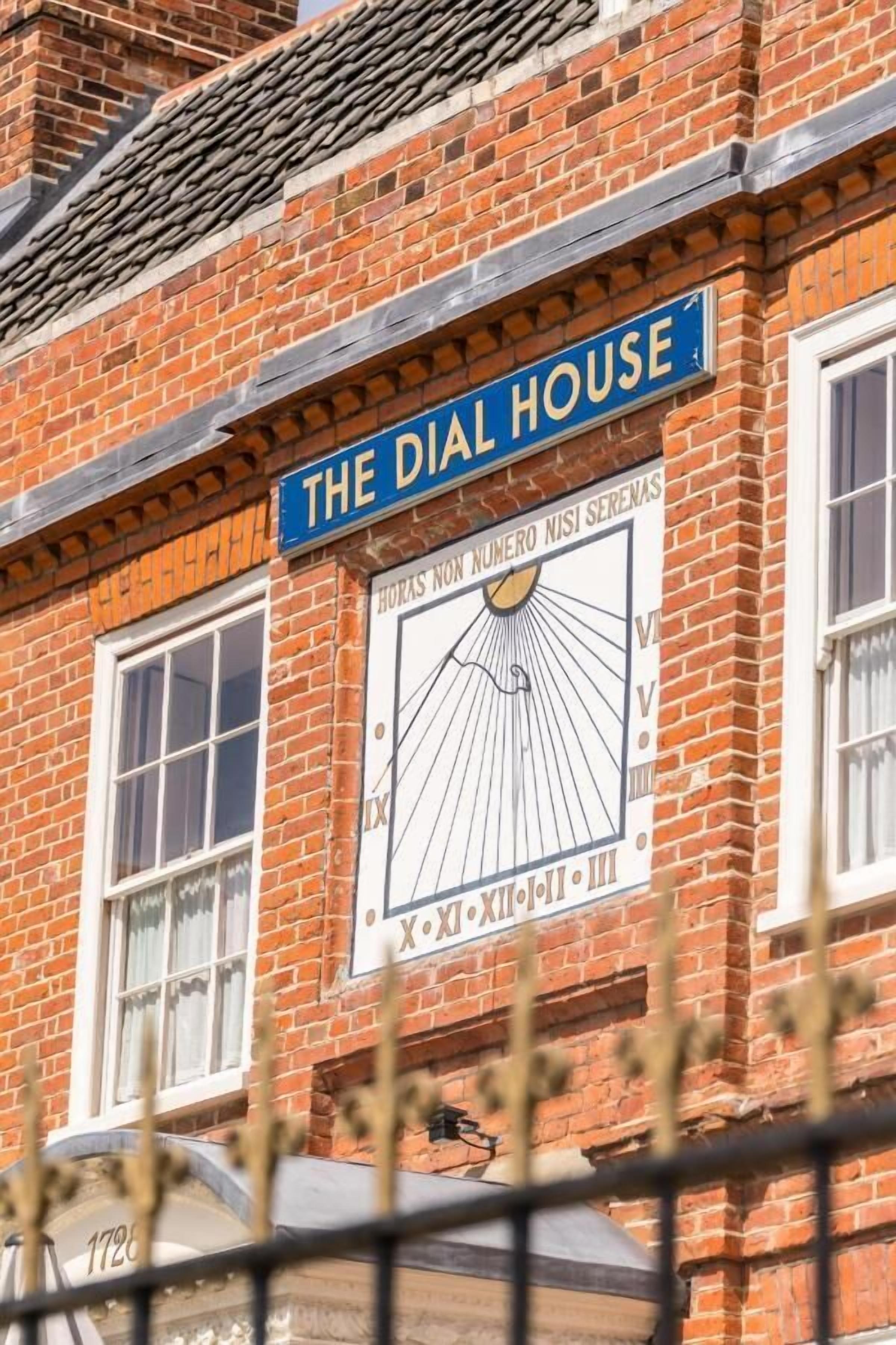 A building with a sign reading "The Dial House" and a large clock with Roman numerals.
